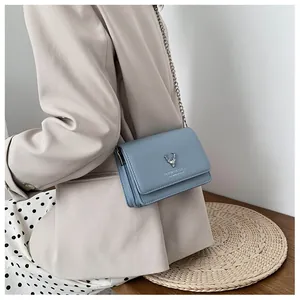 Détail du sac bandoulière bleu clair avec tête de cerf en argent et bandoulière chaîne
