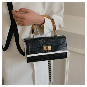 Détail d'un sac à main en cuir crocodile avec poignée en bambou et fermoir doré