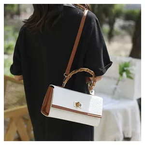 Détail du sac blanc motif crocodile avec poignée en bambou et fermoir en métal doré