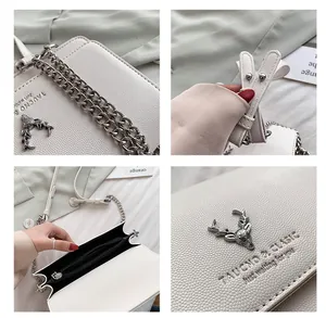 Détails du sac blanc en cuir litchi avec ornement de cerf et bandoulière chaîne