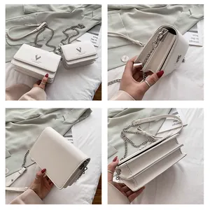 Détail du sac bandoulière blanc crème avec bandoulière chaîne et emblème de cerf