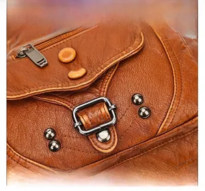 Detail of brown litchi grain leather with antique bronze metal buckle and zipper