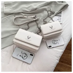 Vue détaillée de deux sacs à chaîne en cuir blanc avec logo cerf argenté et marquage