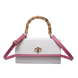 Détail de la poignée en bambou et du cuir croco rose sur le sac à main rétro carré