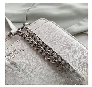 Détail du sac en cuir litchi blanc avec chaîne argentée et décoration tête de cerf