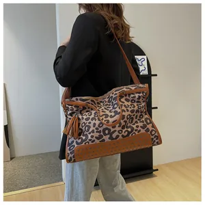 Détail du sac cabas imprimé léopard avec garniture en cuir brun et rivets en bronze