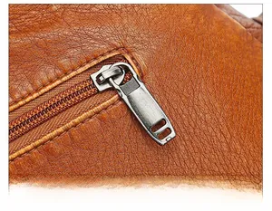 Detailed macro view of the smooth metal zipper pull on a soft leather shoulder bag