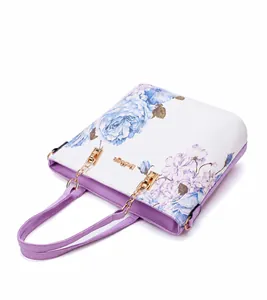 Top-down macro view of floral tote bag showing purple handle and gold chain hardware