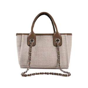 Minimalistische beige Web-Tasche mit braunen Ledergriffen und Metall-Kettenriemen