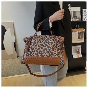 Détail d'un sac cabas léopard avec bordures en cuir marron et rivets métalliques