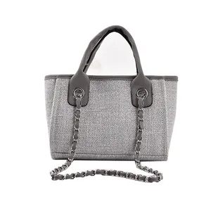 Detailansicht der grauen Stofftasche mit Ledergriffen und silbernen Kettenriemendetails