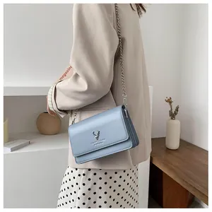 Sac à chaîne bleu clair avec un charm tête de cerf argenté porté par un mannequin