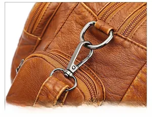 Macro shot of silver metal swivel hook and zipper detail on brown pebble leather bag