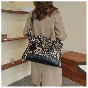 Détail d'un grand sac à bandoulière léopard avec des rivets métalliques et des franges