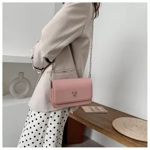 Détail du petit sac rose à chaîne avec logo cerf argenté et texture grainée