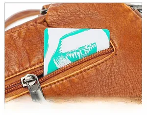Detail of back anti-theft zipper pocket on brown lychee grain faux leather crossbody bag
