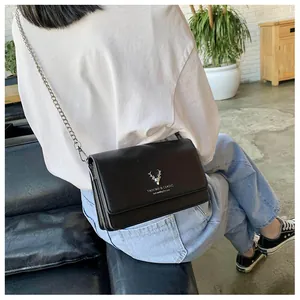 Détail d'un sac bandoulière en cuir noir avec tête de cerf argentée et chaîne métal
