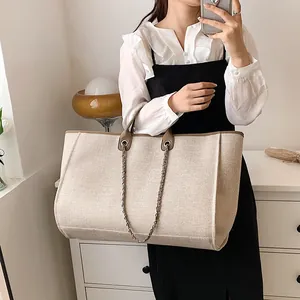 Grande borsa a secchiello in tela beige con finiture in pelle marrone e tracolla a catena