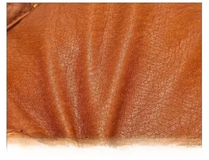 Close-up of soft brown washed leather texture with natural grain on a crossbody bag