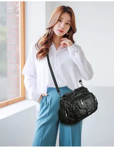 Detailed view of a vintage black multi-pocket crossbody bag worn by a model in bright light