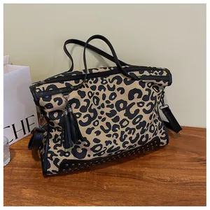 Gros plan du sac cabas en toile léopard avec rivets noirs et pompons en cuir