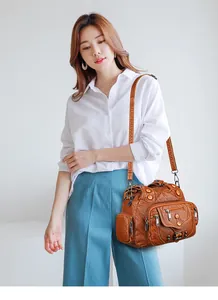 Brown vintage multi-pocket crossbody bag styled with white shirt and blue pants