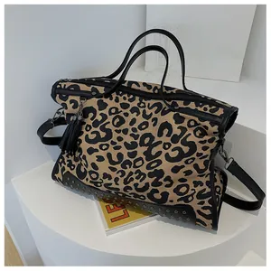 Détail du sac cabas en toile léopard avec pompon à franges noires et rivets dorés