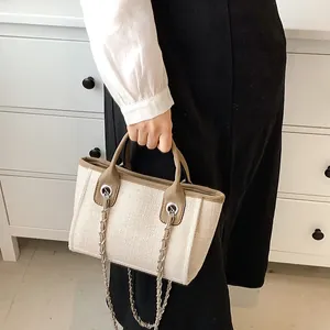Elegante borsa a secchiello intrecciata beige con finiture in pelle e tracolla a catena