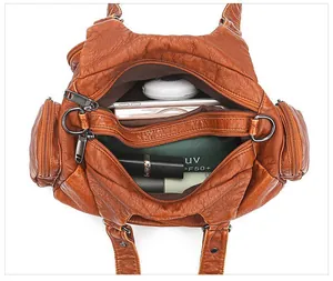 Top view of spacious brown soft leather bag interior with tablet and cosmetics