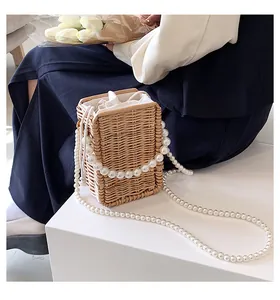 Detail of woven straw bucket bag with large faux pearl handles and drawstring liner
