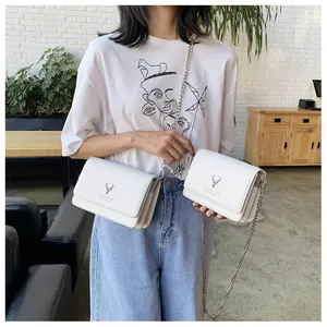 Détail du petit sac blanc en cuir avec logo de cerf argenté et bandoulière en chaîne
