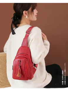 Dettaglio della borsa a tracolla rossa in pelle PU con cerniera e nappa su una modella