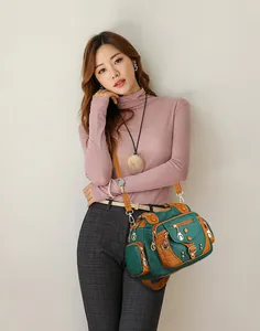 Macro detail of multi-pocket crossbody bag with green and tan contrasting pebbled leather
