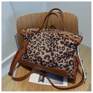 Détail d'un sac cabas en toile léopard avec rivets métalliques et glands en cuir