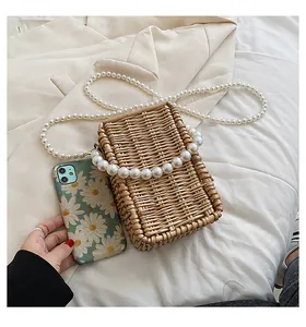 Detailed view of woven straw bag with pearl handle and shoulder strap for elegant style