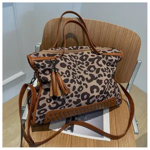 Détail du sac en toile léopard avec glands en cuir et rivets métalliques sur le bord