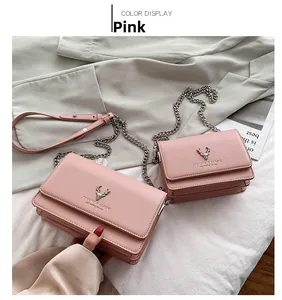 Détail de sacs bandoulière en similicuir rose avec logo cerf et chaîne argentée chic