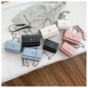 Détail de sacs à bandoulière colorés avec ornement cerf en métal et chaînette