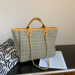 Detail of yellow tweed tote bag with metal chain strap and zebra print dust bag