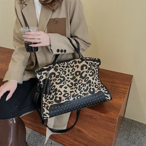 Grand sac cabas léopard avec rivets et pompons présenté dans une scène de mode urbaine