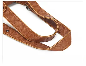 Detailed close-up of brown soft leather shoulder strap with gunmetal hardware and stitching