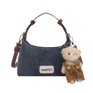 Sac cabas minimaliste en denim bleu avec lanières en cuir brun et pendentif ours