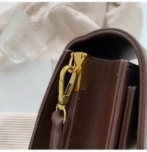 Gros plan sur les ferrures métalliques dorées durables d'un sac à bandoulière en cuir.