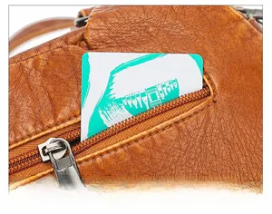 Detailed view of the back anti-theft zipper pocket on brown textured leather tote bag
