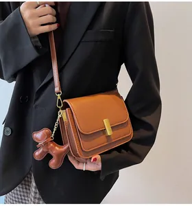 Sac bandoulière carré marron élégant pour femme avec un charmant détail de breloque chien.
