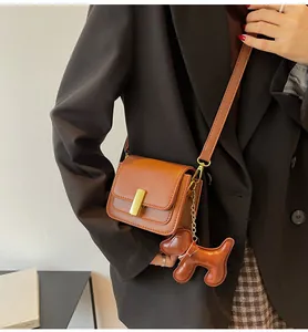 Vue détaillée d'un sac à bandoulière carré en similicuir marron avec breloque chien
