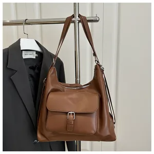 Detail of a brown faux leather tote bag showing the front buckle pocket and zipper closure