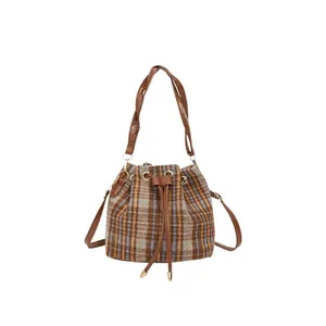 Bolso tipo cubo de cuadros con cordón, correas de cuero marrón y herrajes dorados