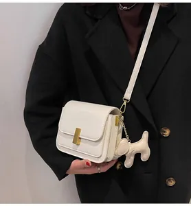 Gros plan sur un sac bandoulière blanc carré avec un charmant pendentif chien