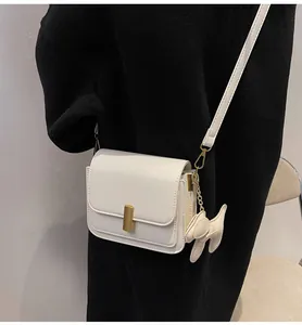 Petit sac bandoulière blanc en cuir avec fermoir doré et breloque chien sur noir
